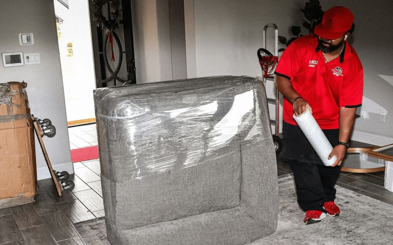 Mover handling a wrapped sofa in a home during a move.