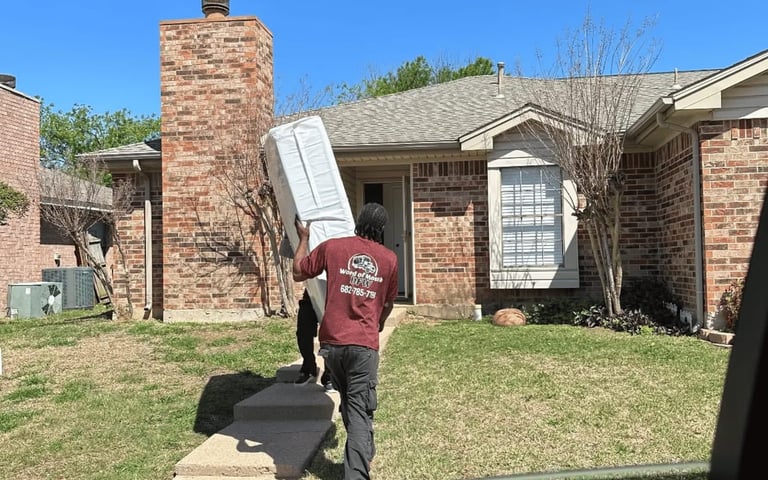 Mover carries large appliance up steps to a brick house.