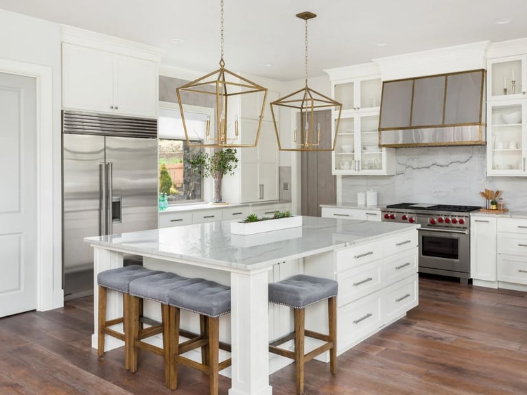 Modern kitchen with white cabinetry, marble island, and gold pendant lights.