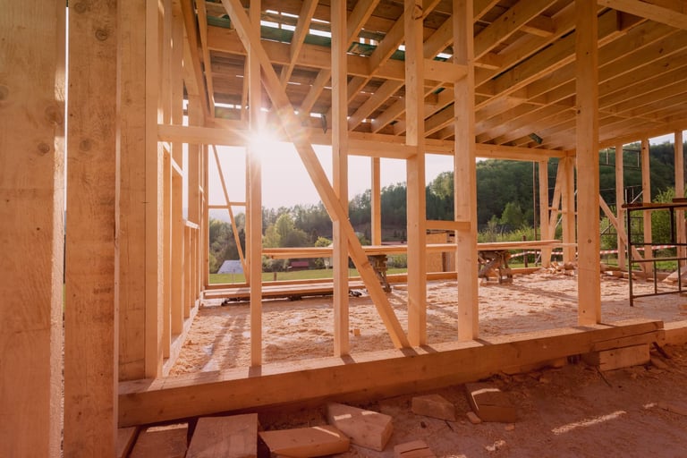 Wooden frame of a house under construction with sunlight streaming through.