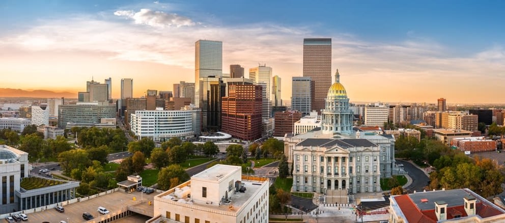 Aerial view of a city skyline with a domed capitol building at sunset.