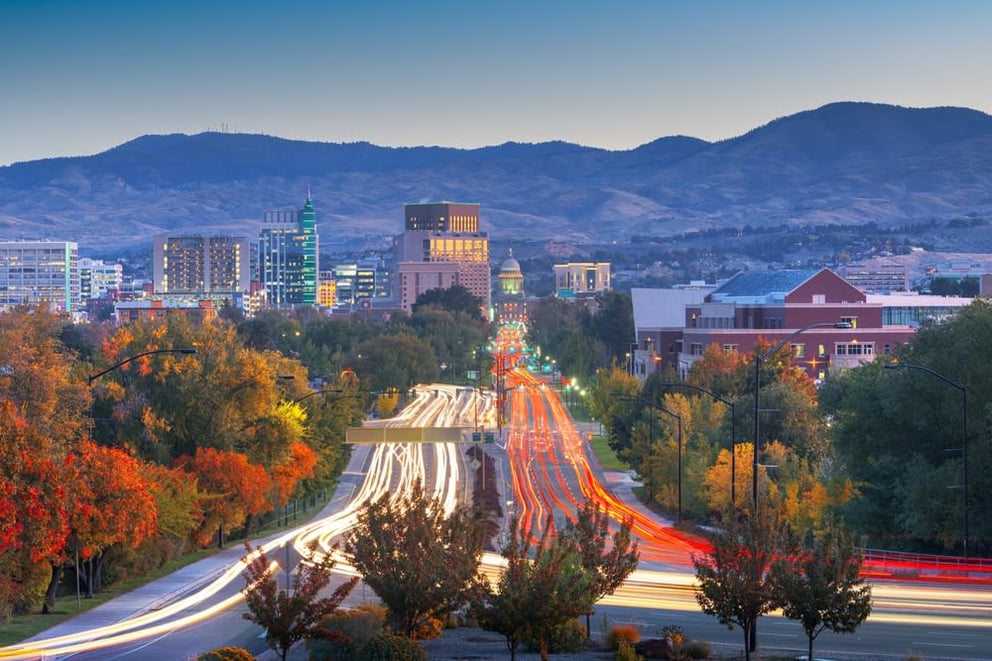City skyline at dusk with streaked traffic and autumn trees.
