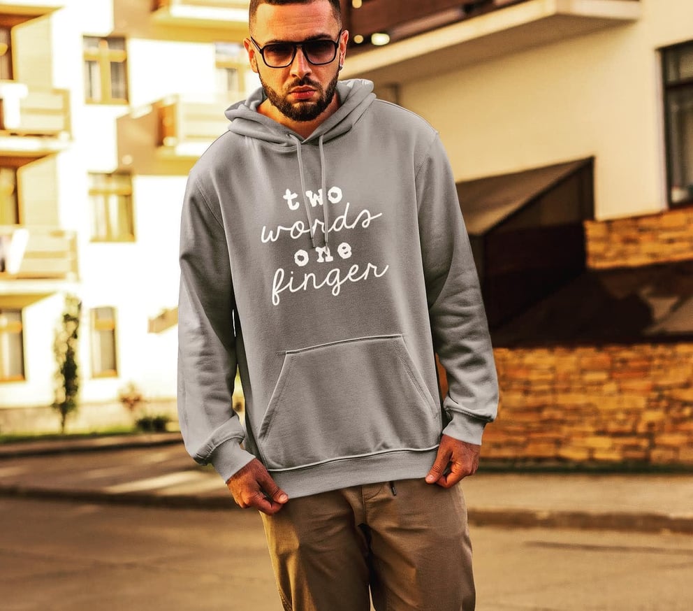 Man in grey hoodie with text standing on street