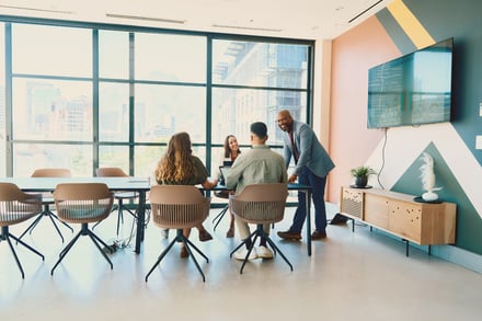 Four professionals collaborating around a modern conference table near large windows.