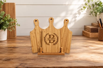 Three bamboo cutting boards with monogram stand on wooden table