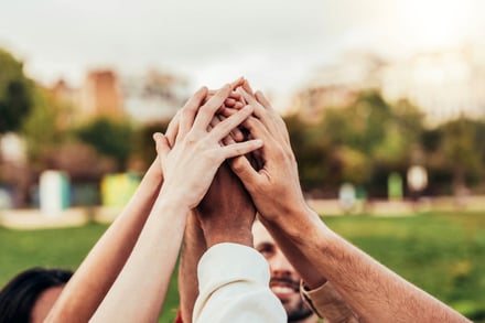 Hands stacked together in a team gesture outdoors.