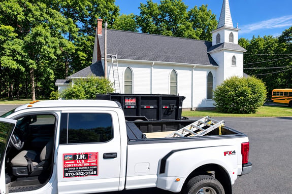 White pickup truck with construction tools parked in front of a white church.