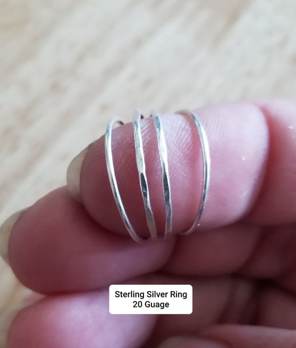 Close-up of a hand wearing a thin silver ring on a finger.