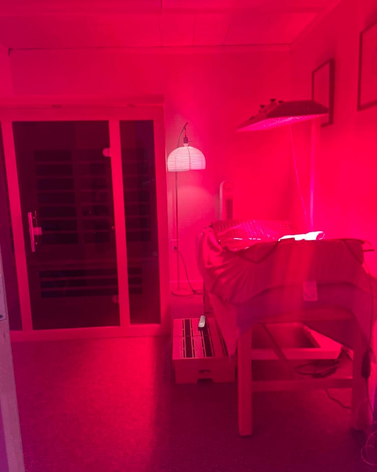 Red-lit therapy room with bed, lamp and glass door