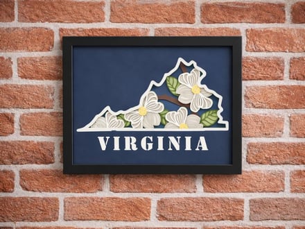 Framed Virginia state art with dogwood flowers on brick wall
