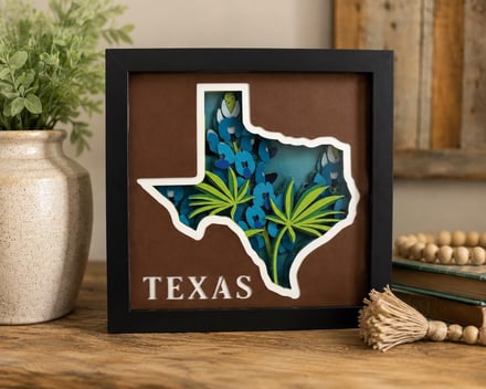Texas state outline art with bluebonnets and palm fronds in a black frame.