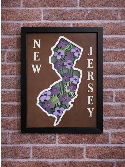 Framed New Jersey state map art with purple flowers and brown background.