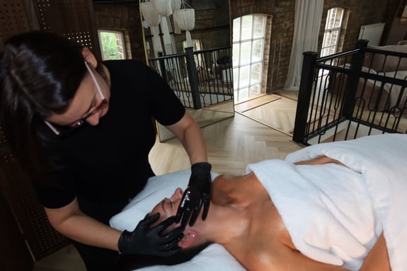 A therapist applies a facial treatment to a client in a spa setting.