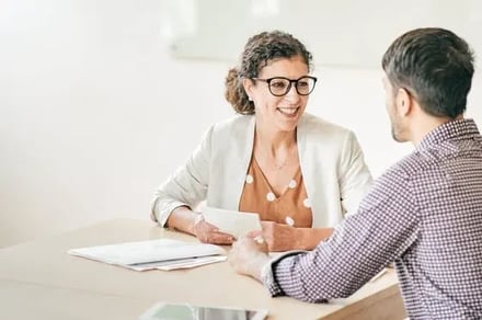 Two people in a meeting over documents at a table.