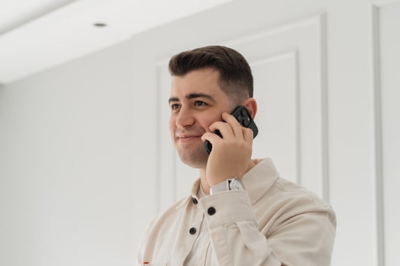 Man in light shirt talking on phone in minimalist room.