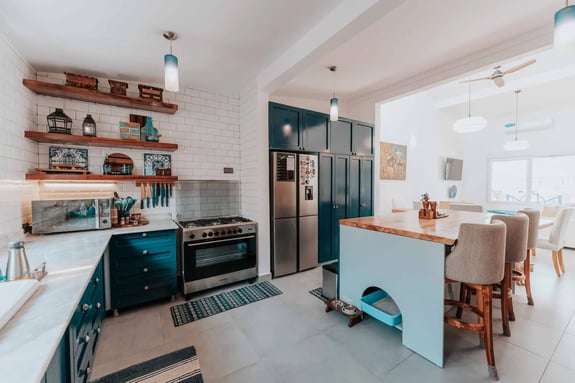 Modern kitchen with teal cabinets, white subway tiles, and a central island.