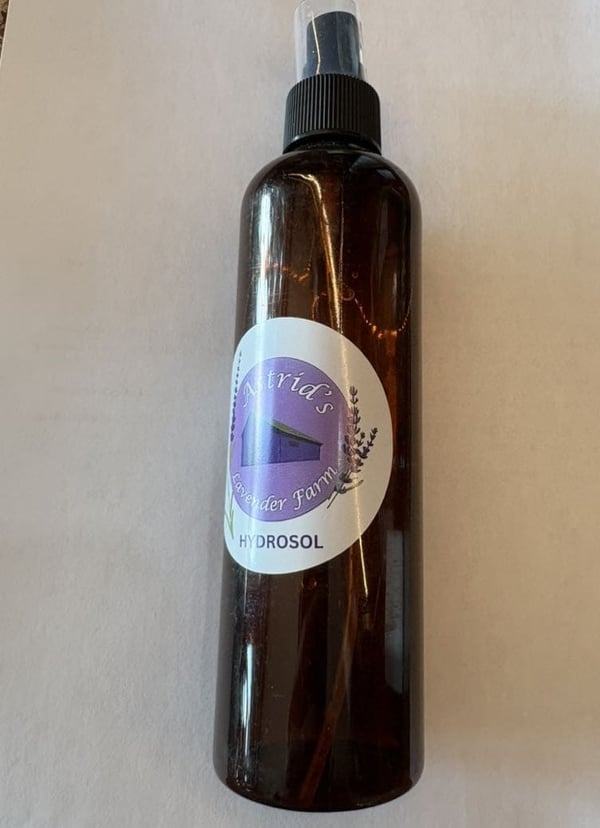 A branded amber spray bottle with a label showing lavender and a farm.