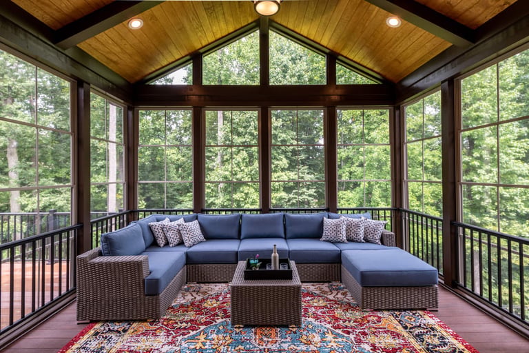 A covered porch with a sectional sofa and coffee table under a vaulted ceiling.
