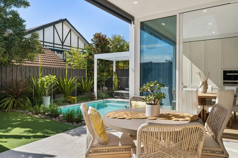 Modern outdoor dining area with wicker chairs and a pool view.