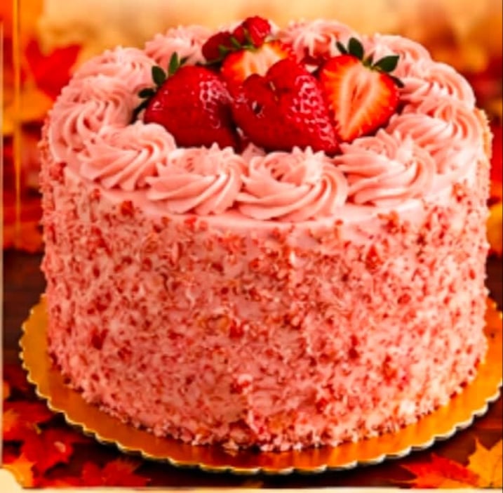 A strawberry cake with piped frosting and fresh berries on a decorative plate.