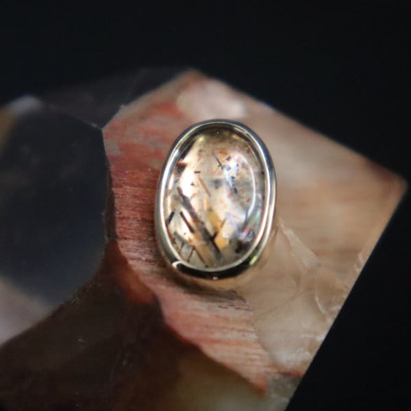 A silver ring with a patterned stone set on a polished stone base.