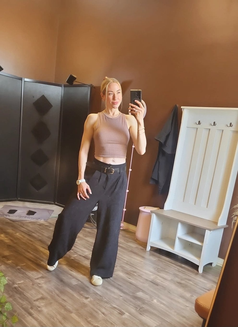 Woman in casual workout wear taking a mirror selfie in a cozy room.