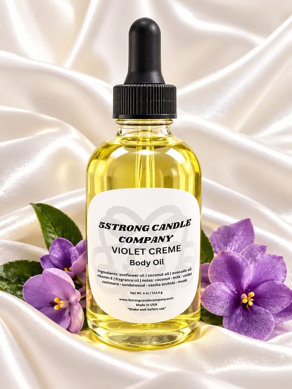 A glass bottle of body oil with a dropper cap and purple flowers on silk.