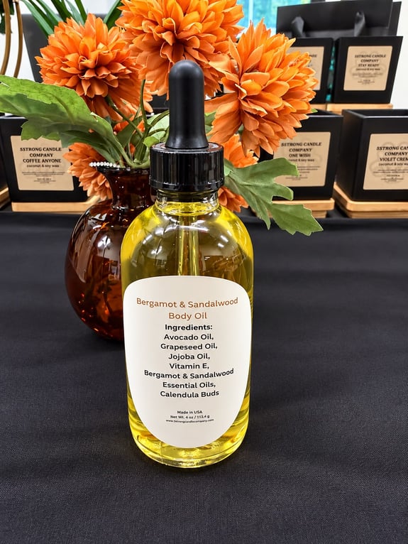 A glass bottle of body oil with a dropper cap sits on a black tablecloth.