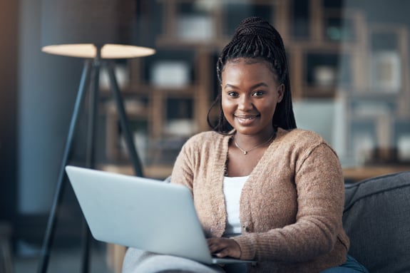 Laptop, relax and portrait of black woman on sofa for streaming service, smile and movie subscription. Online film, entertainment and multimedia search with person in living room of home for break