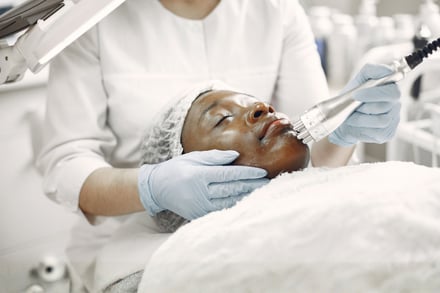 A technician applies a facial treatment with a handheld device in a spa.