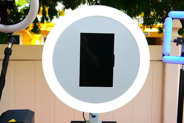 A circular LED light ring mounted on a stand outdoors.