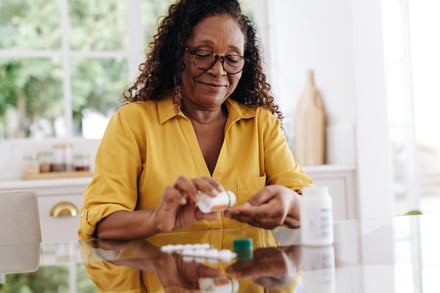 Senior woman carefully taking her prescription medication as part of her daily routine. Mature woman committing to her treatment plan as part of her chronic disease management at home.