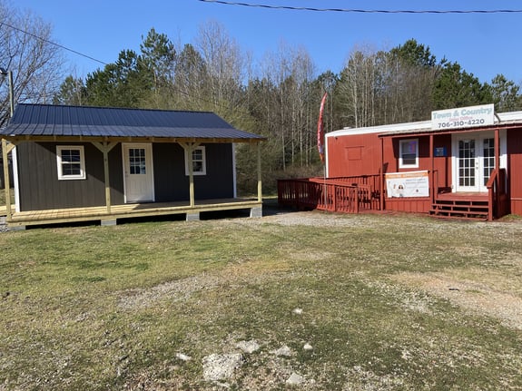 Two rustic cabins with porches in a grassy yard under clear blue sky