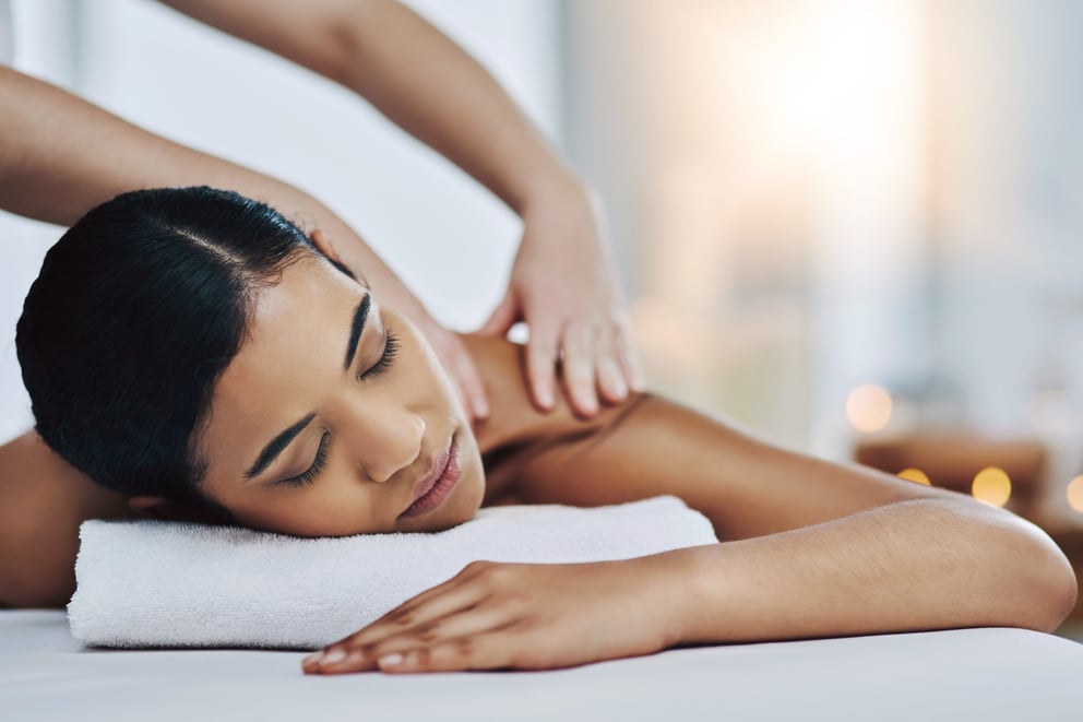 Hands, woman and rest with back massage at spa for stress relief, muscle healing and skincare. Bokeh, people and physical therapy with masseuse, therapeutic treatment and pamper session for wellness