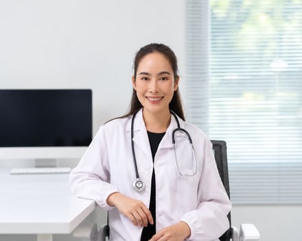 A smiling female doctor in a white coat with a stethoscope.