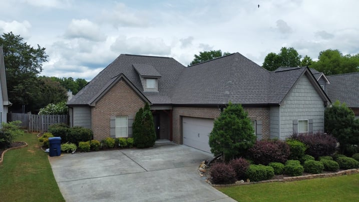 Single-story suburban home with gray shingle roof and brick facade.