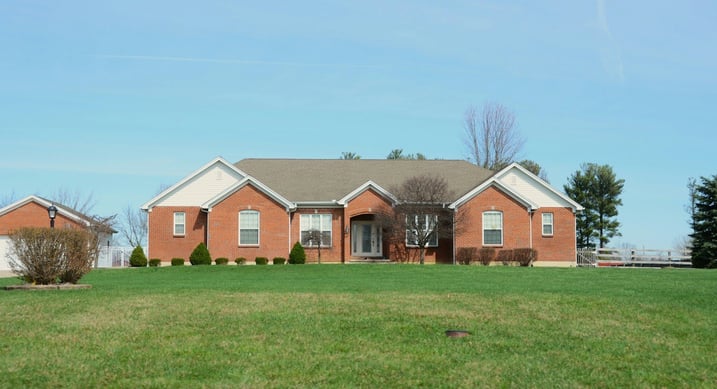 Single-story brick home with white trim and green lawn under clear sky
