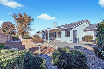 Single-story suburban home with covered porch and gravel landscaping under clear sky