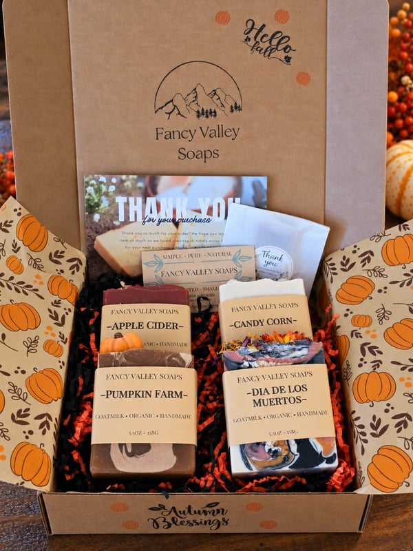Open gift box filled with autumn-themed soaps and thank-you cards.