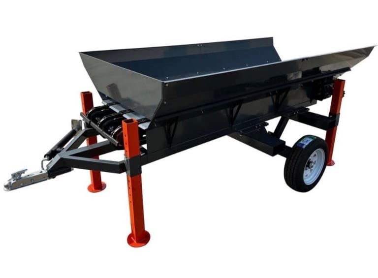 Black metal trailer with red legs and single wheel for hauling bulk materials.
