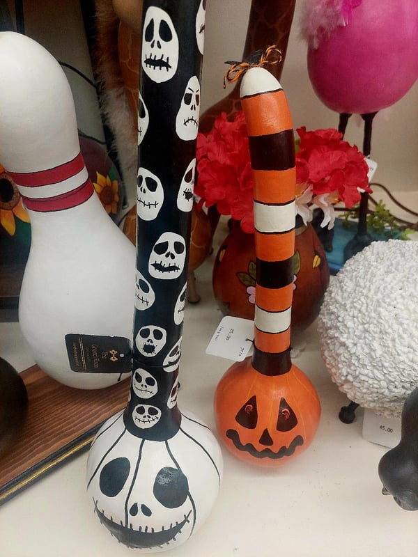 Three Halloween-themed bowling pins with Jack Skellington and pumpkin designs on a shelf.