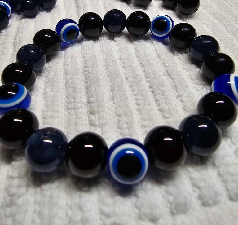 A bracelet of black and blue evil eye beads on a textured white towel.