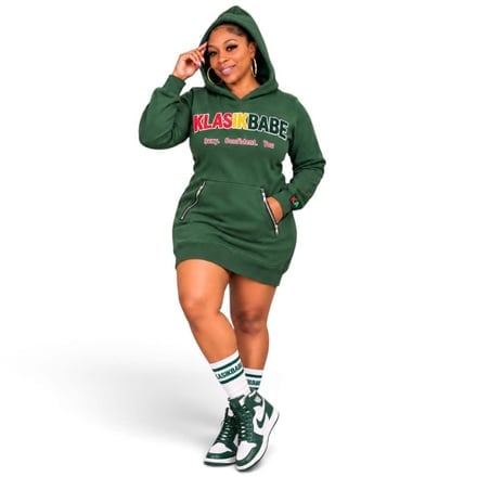 Woman in green hoodie dress posing with hand on head.