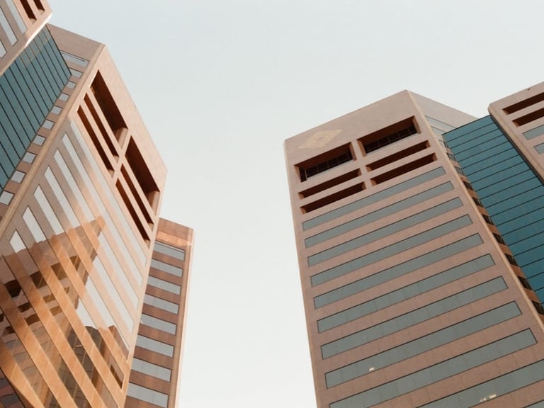 Low-angle view of modern office towers against a pale sky