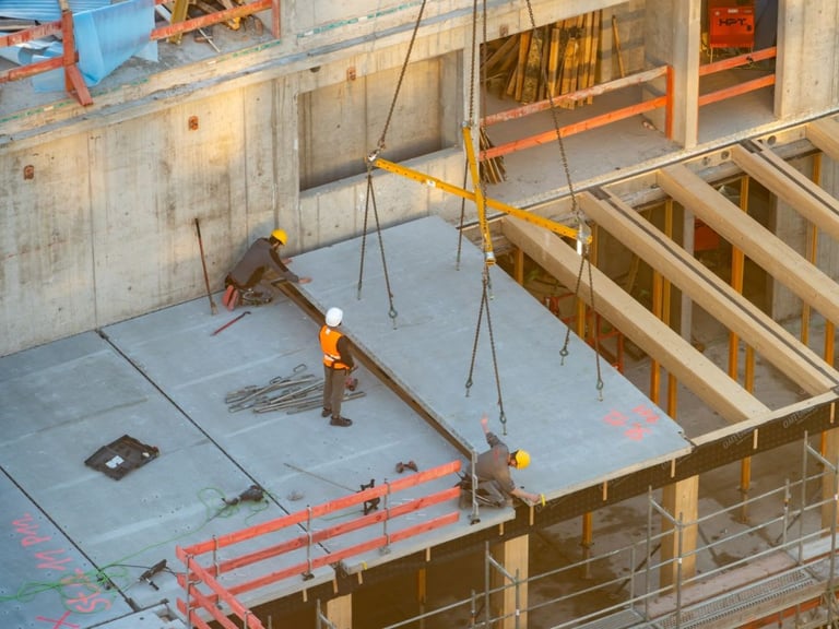 Construction workers installing steel beams on a high-rise floor.