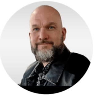 Bald man with beard in black leather jacket, headshot against plain background.